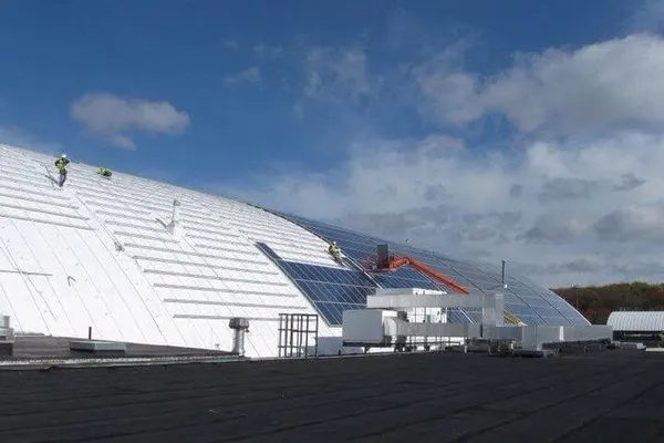 Wanex technicians installing solar panels on a large domed commercial roof